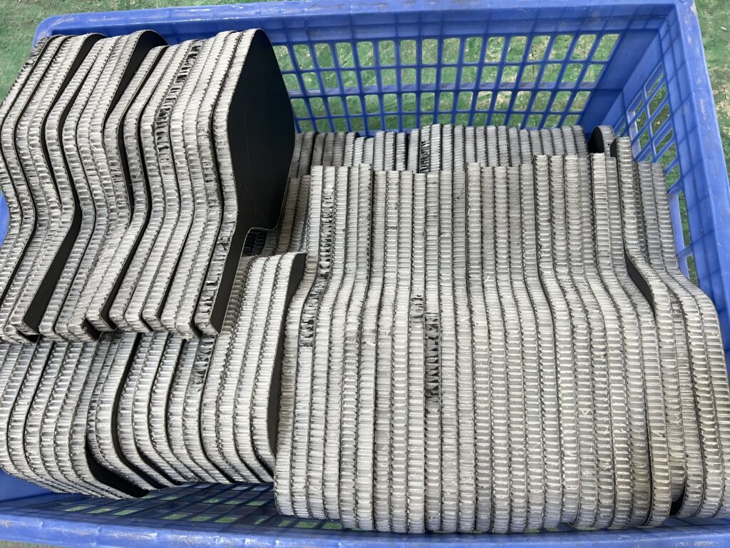 Cold-press pickleball paddle production workshop with CNC cutting machines and stacked raw paddle sheets, showing industrial manufacturing of composite paddles