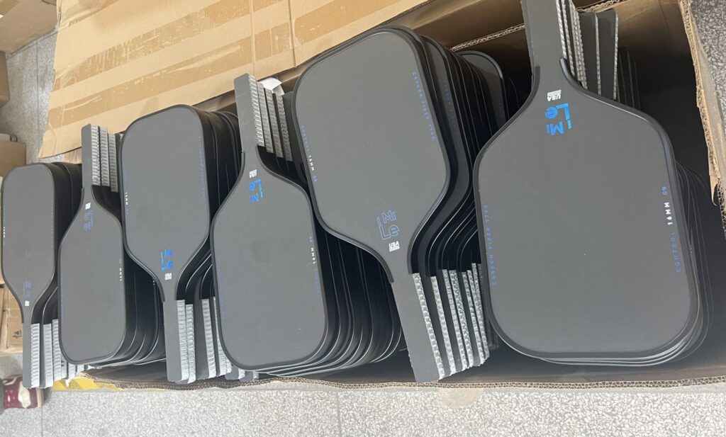 Thermoformed carbon fiber pickleball paddles in bulk production inside a professional paddle manufacturing factory