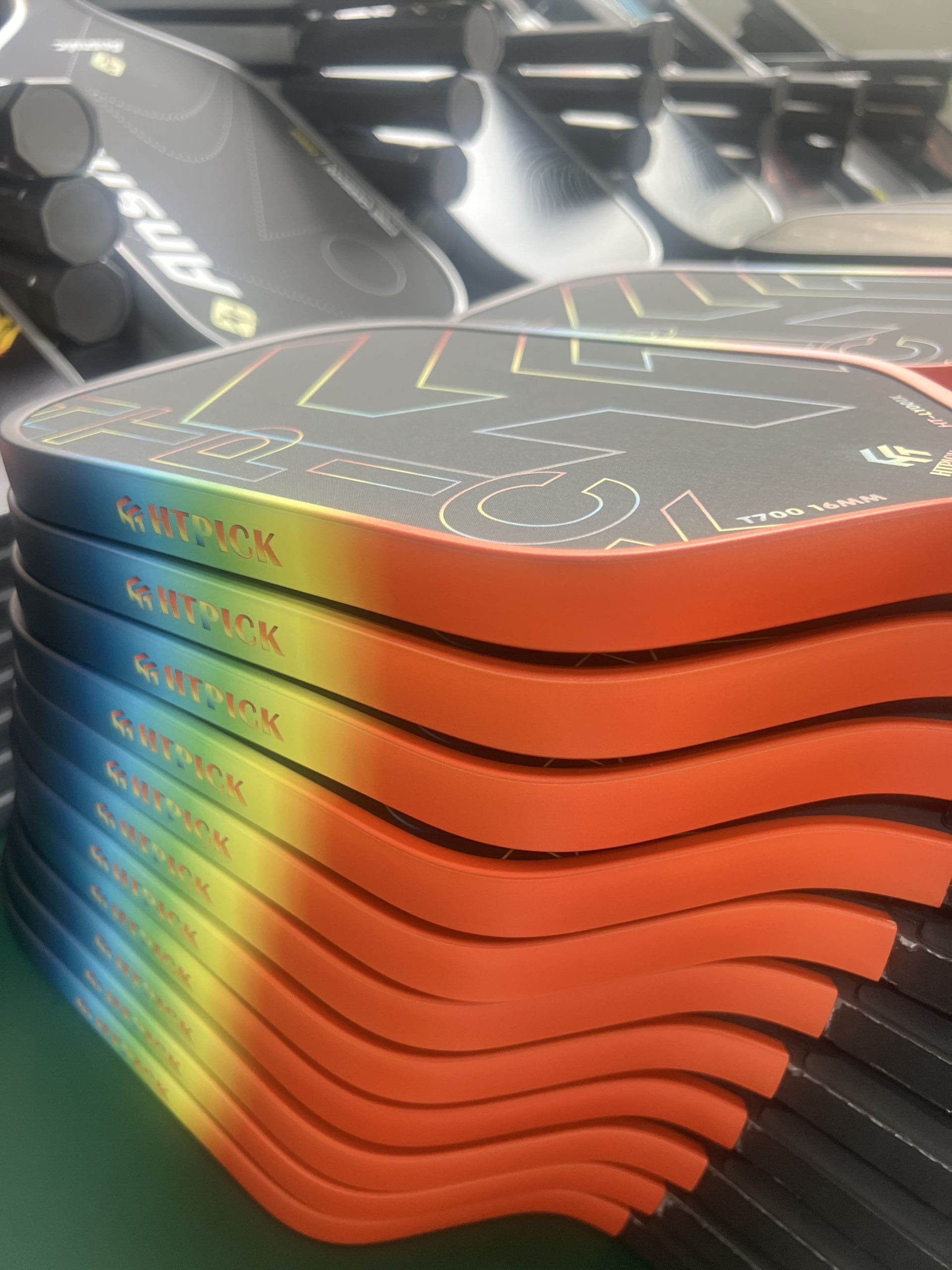 Pickleball paddle production workshop showing large batches of custom carbon fiber paddles in multiple colors, ready for assembly and packaging from a professional manufacturing factory